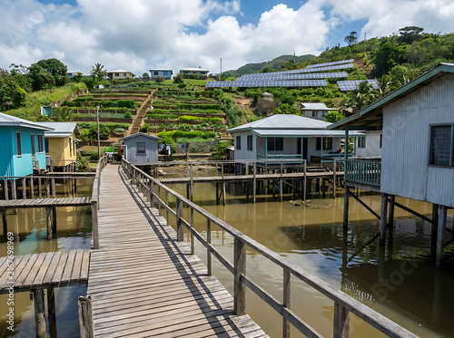 Картината върху платно Sustainable stilt village with solar panels and terraced farming showcasing clim