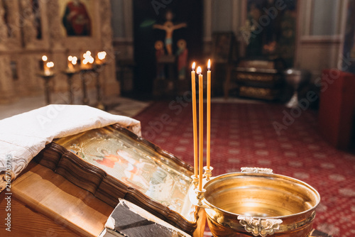 Obraz na płótnie Sacred Vigil: Three lit candles flicker softly in the solemn interior of a church, casting a gentle glow on an ornate religious relic