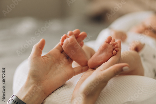 Canvas Print Newborn Feet: A gentle parent's hands cradle the tiny, delicate feet of a newborn baby, capturing a tender moment of early parenthood and pure innocence