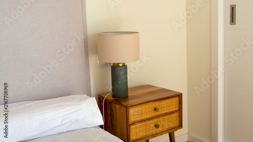 A nightstand with a lamp next to the bed.