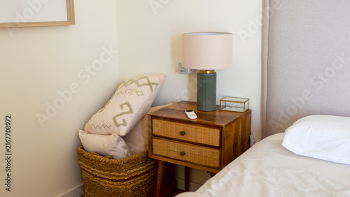 A nightstand with a lamp next to the bed.