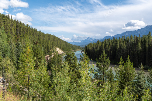 Morant's Curve in Banff National Park, Canada, with the Bow River winding through dense forest beneath the dramatic Canadian Rocky Mountains on a scenic summer day.