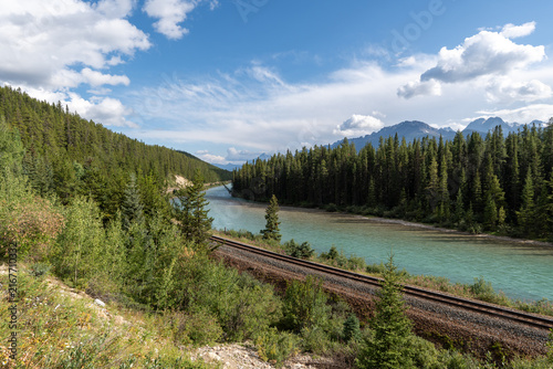 Morant's Curve in Banff National Park, Canada, with the Bow River winding through dense forest beneath the dramatic Canadian Rocky Mountains on a scenic summer day.
