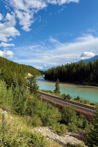 Morant's Curve in Banff National Park, Canada, with the Bow River winding through dense forest beneath the dramatic Canadian Rocky Mountains on a scenic summer day.