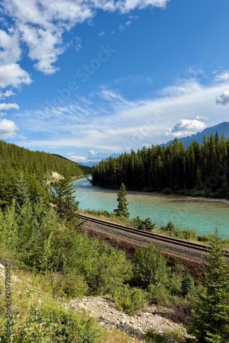 Morant's Curve in Banff National Park, Canada, with the Bow River winding through dense forest beneath the dramatic Canadian Rocky Mountains on a scenic summer day.