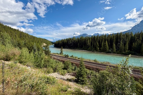 Morant's Curve in Banff National Park, Canada, with the Bow River winding through dense forest beneath the dramatic Canadian Rocky Mountains on a scenic summer day.