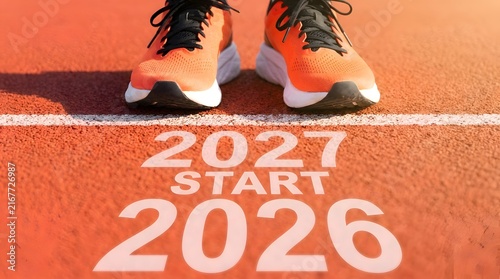 Close up view of orange athletic sneakers standing on a red running track with conceptual text overlay representing a transition between two different calendar years for goals