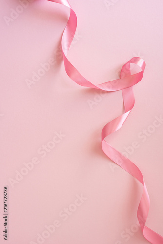 Pink ribbon for Breast Cancer Awareness Month on soft vertical pink background with elegant satin curl