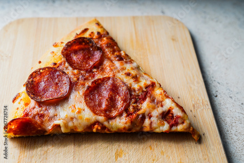 Pepperoni pizza slice on wooden board