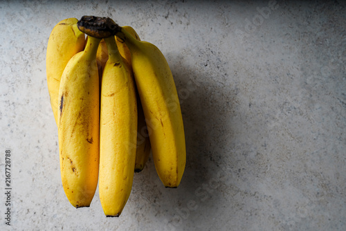 Bunch of ripe yellow bananas hanging against wall
