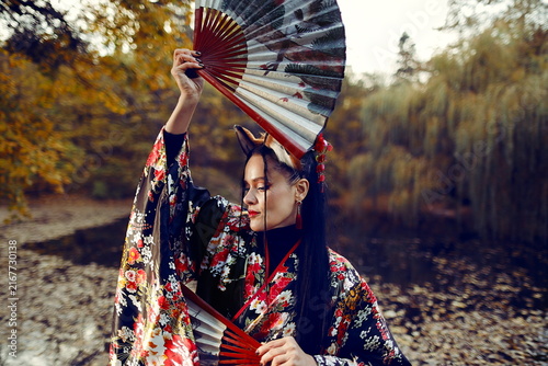 Japanese Kitsune Fantasy Woman in Kimono with Fans in Autumn Park