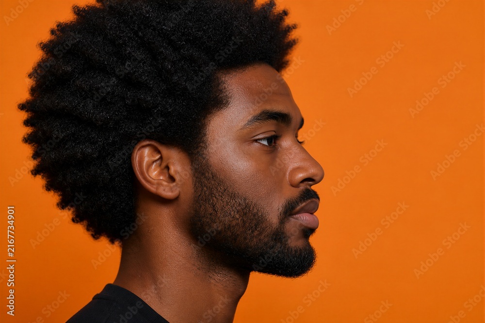 Obraz premium Young man with afro hairstyle posing against orange background