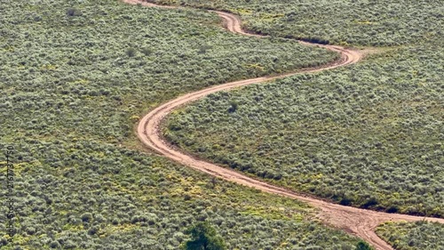 Truck drives along a winding dirt road through open woodland and sagebrush near Duck Creek in Dixie National Forest, Utah.