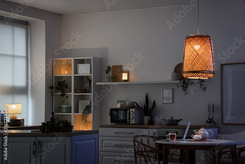 Cuadro en lienzo Cozy evening home atmosphere, kitchen interior with warm lighting and laptop on