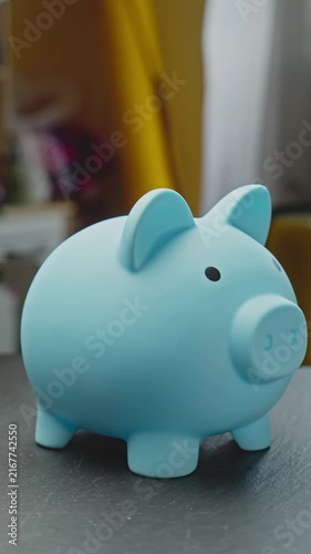 Blue piggy bank rotating. Financial planning, saving and investment growth concept. Vertical video. Close-up in 4K, UHD