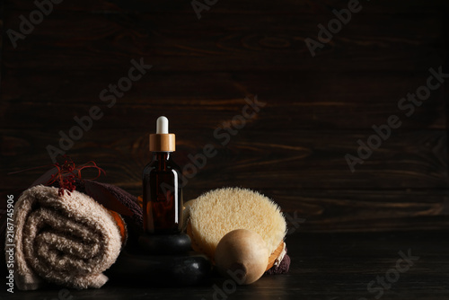 Bottle of essential oil and spa accessories on dark wooden background