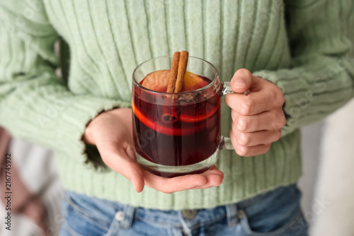 Konstfotografi Woman holding glass cup of hot mulled wine at home, closeup
