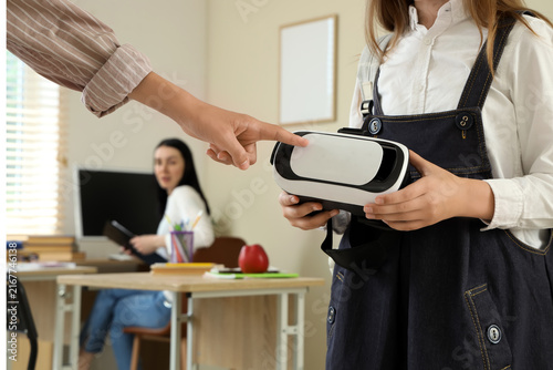 Teenage girl showing VR glasses to her classmate at school, closeup