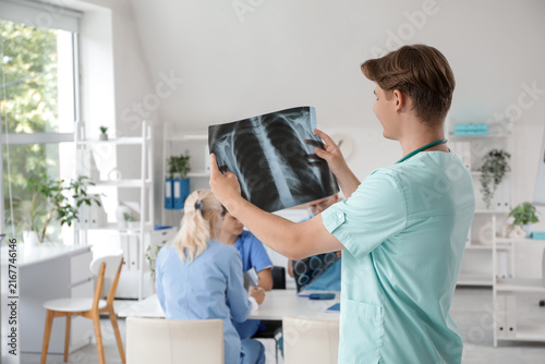Young male doctor with x-ray image of lungs in clinic