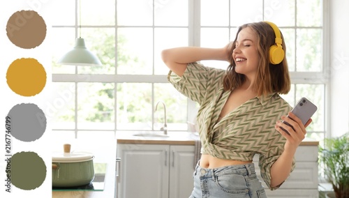 Joyful home entertainment and relaxation  young woman dancing with headphones and smartphone in a modern kitchen