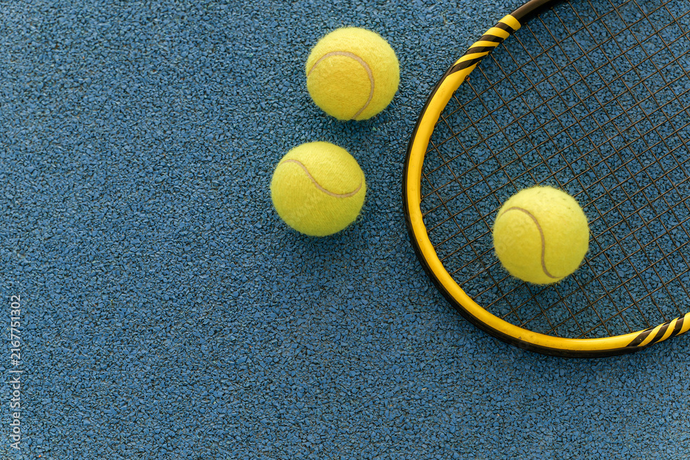 Naklejka premium Tennis racket and balls on a blue court surface, ready for a game