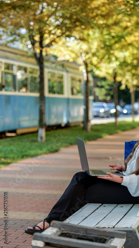 Photography Woman working on laptop on bench near tram and trees in autumn park