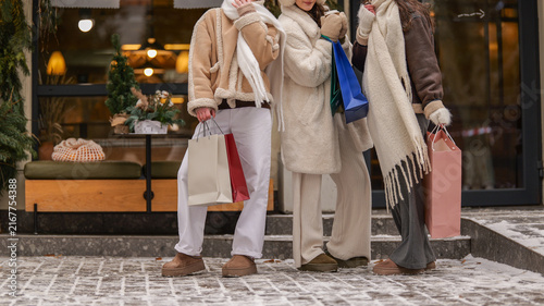 Bild auf Leinwand Friends enjoying winter shopping spree with bags outside a boutique