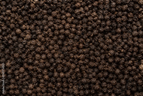 Black peppercorns piled covering surface closeup texture