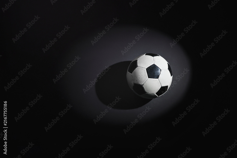 Naklejka premium A soccer ball on the rough concrete floor in the spotlight.