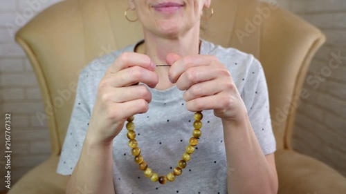 Tiger's eye rosary. Woman fingering a yellow tiger's eye rosary