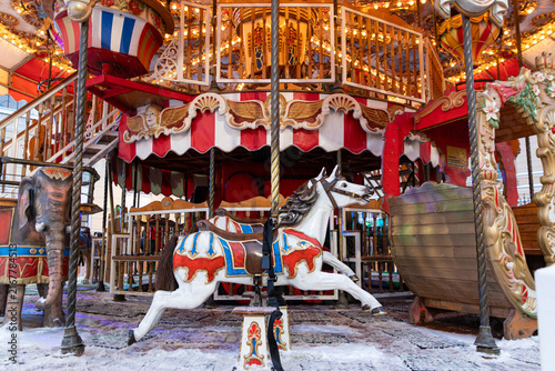 Carousel with colorful horses in an amusement park. Merry go round. The concept of Christmas holidays and school holidays. Christmas winter market