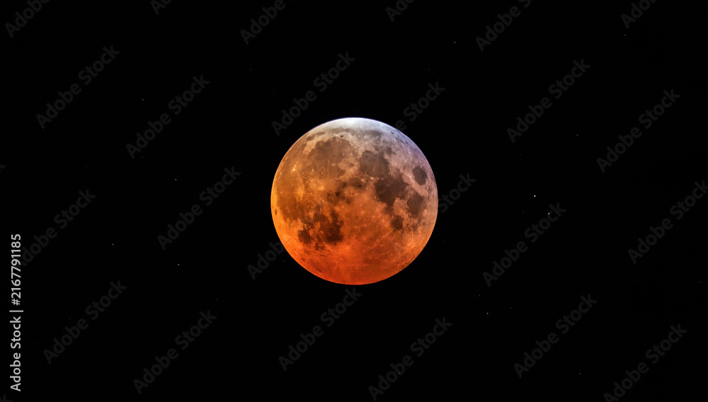 Naklejka premium A full moon appearing red during partial lunar eclipse.