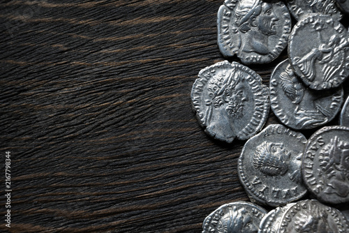 Фотография Top view of ancient Roman silver coins on a dark textured background