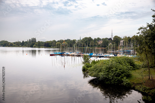 Sailing boats moored at a marina on the Außenalster beneath a morning sky in Hamburg, Germany.