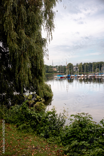 Sailing boats moored at a marina on the Außenalster beneath a morning sky in Hamburg, Germany.