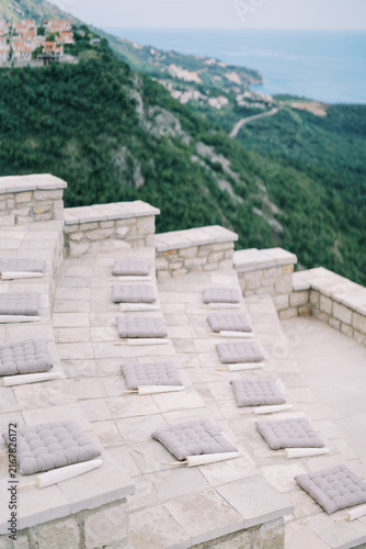 Stone Terrace Seating With Cushions and Parasols Overlooking Coastal Hillside