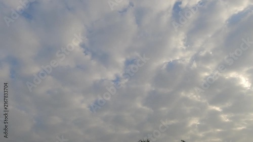 Cinematic view of thick fluffy clouds covering the daytime sky. Serene natural background showing overcast weather conditions with subtle sunlight passing through beautiful cloud formations.