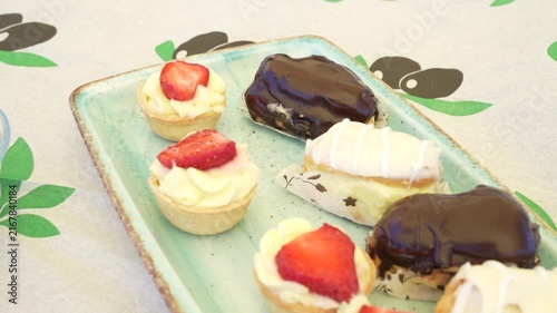 Assorted sweet mini pastries with fruit tarts and eclairs on a plate