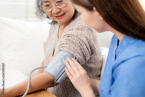 Asian woman nurse measuring blood pressure senior patient, medical checking for hypertension monitoring, caregiver support elderly woman with arterial blood pressure device, routine health checkup.