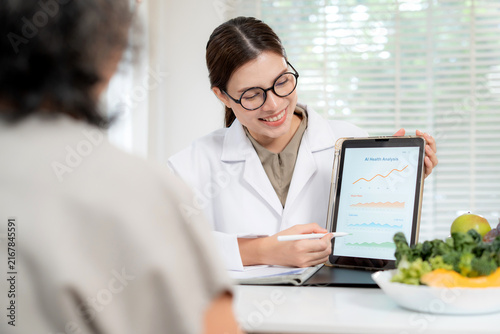 Asian nutritionist showing AI health analysis graph on tablet to senior patient, doctor using technology for medical data tracking, medical diagnosis for diet control, consulting and nutrition.