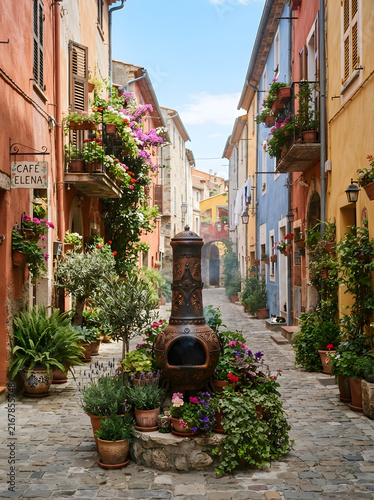 Rustic medieval italian alley decorated with vibrant flowers and outdoor chimney stove for travel inspiration.