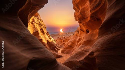 Narrow slot canyon sandstone walls illuminated by crescent solar eclipse sunset creating mysterious golden desert landscapes.