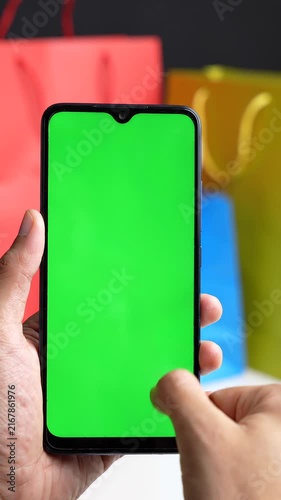 Person Holding a Smartphone with a Green Screen Chroma Key Display for Digital Shopping App Mockup Development