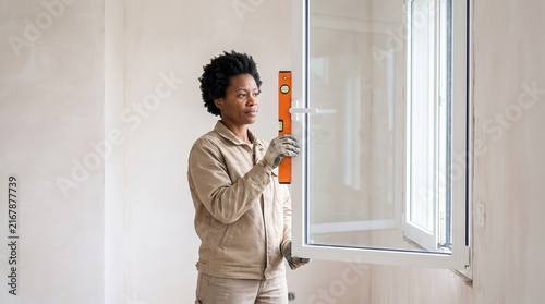 A woman using a spirit level to check the accuracy of a window installation.