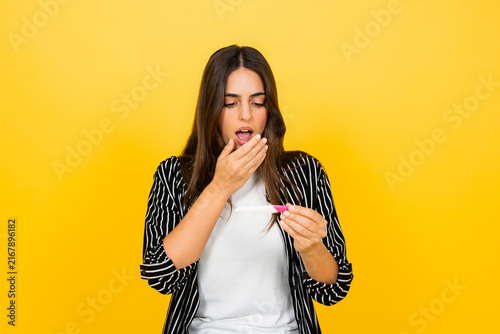 Bild auf Leinwand Young woman looking shocked and surprised after seeing a positive pregnancy test
