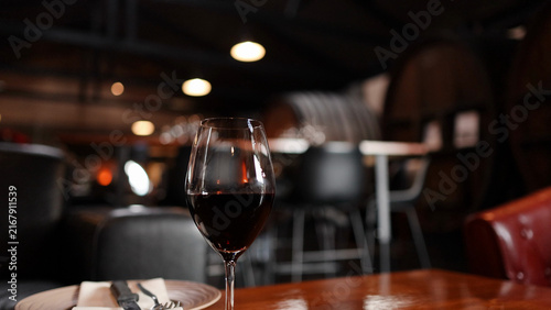 Quadro su tela Glass of Red Wine on Wooden Table in Rustic Cellar