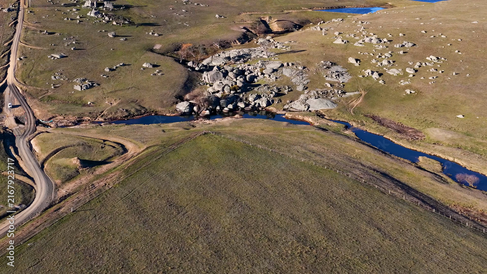 Fototapeta premium Aerial View of Rural Landscape with Granite Boulders and Winding Stream