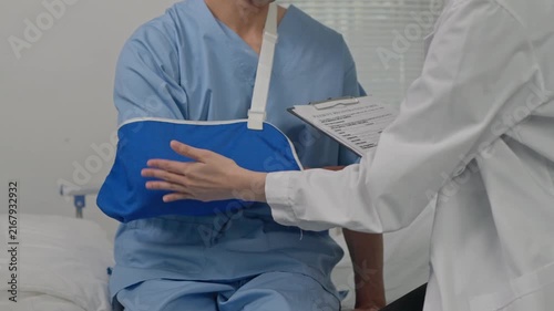 Doctor examining patient with broken arm in a sling