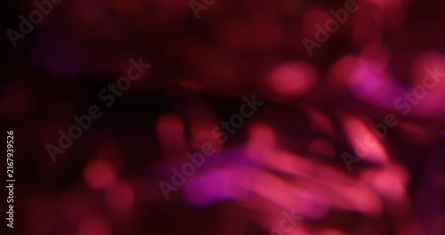 Bokeh light. Pink glitter texture. Vibrant purple color lens flare bright optical glisten reflection on abstract illuminated black background.