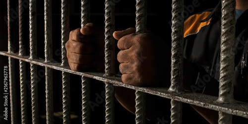 Obraz na płótnie prisoner's hands behind bars with black background